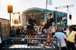 British Sign Language Interpreters signing a performance at the main stage to people from the viewing platform while the sun sets